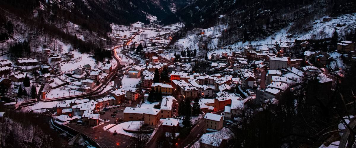 A snow-covered village nestled in a valley with mountains in the background.
