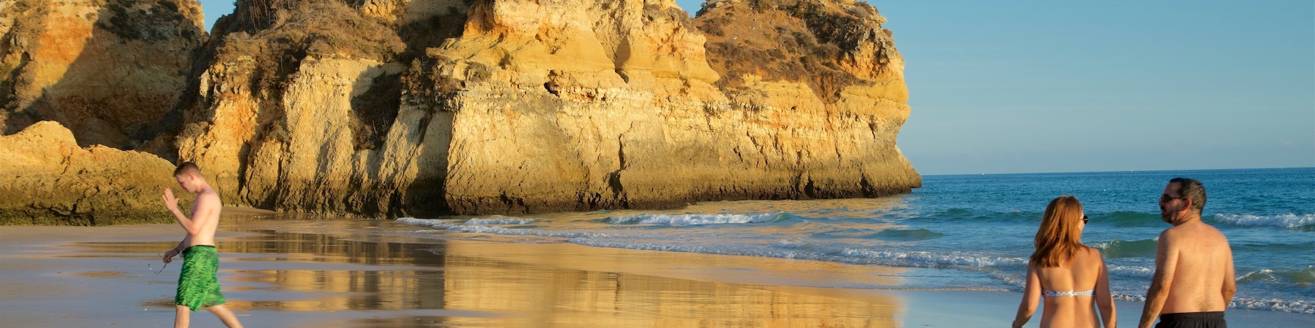 A beach with rocky cliffs and calm waves.