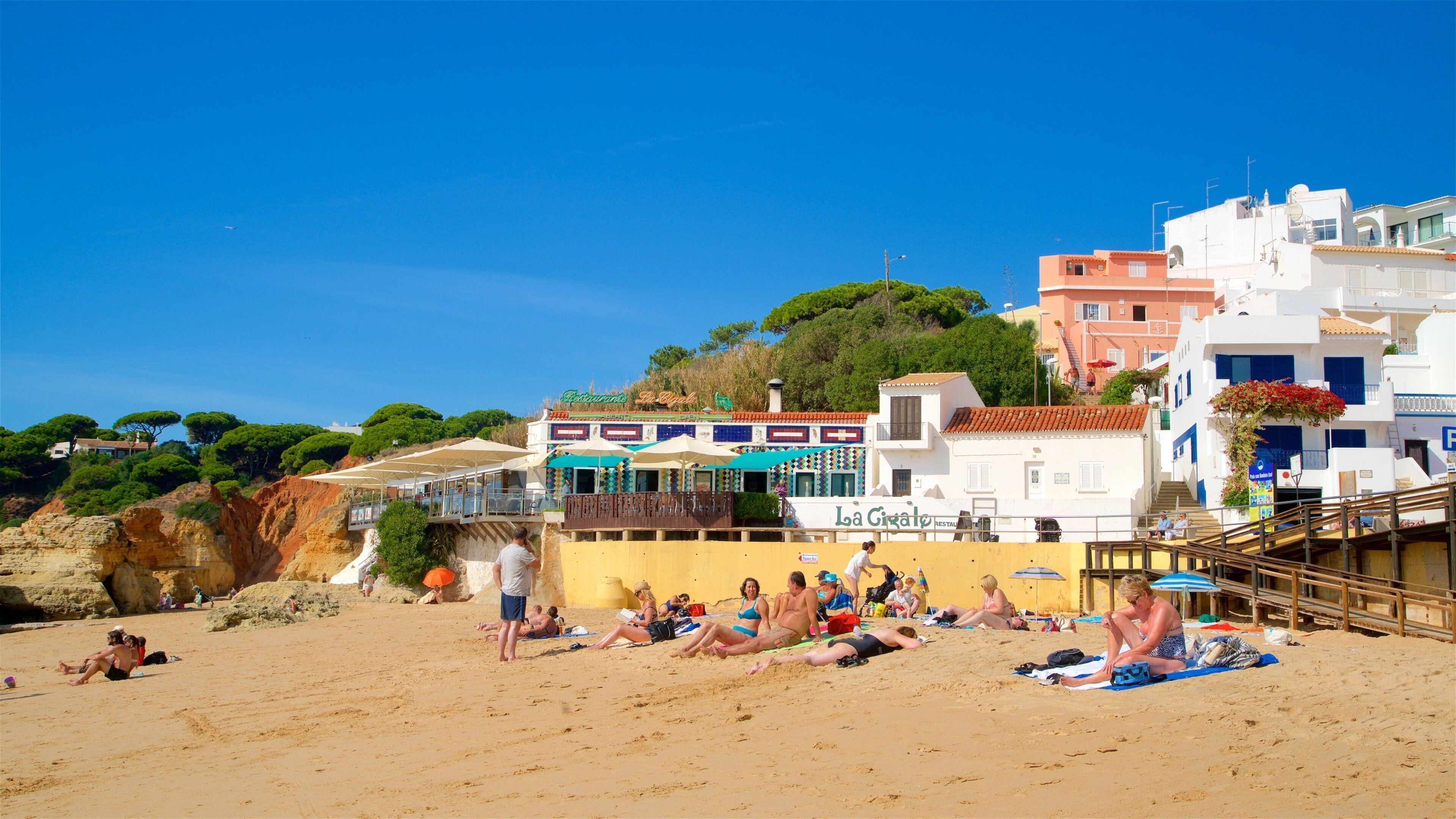 A beach with people sunbathing and a restaurant named 'La Givolo' in the background.