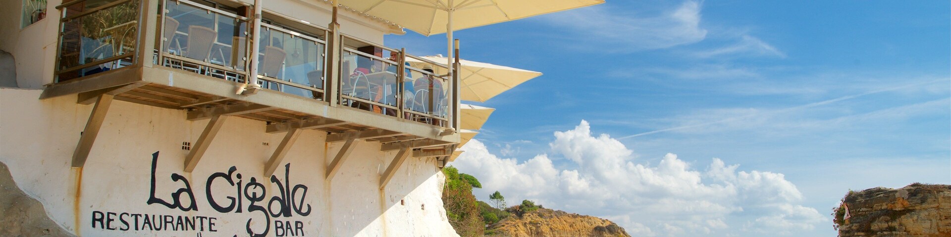 Olhos D\'Agua Beach which includes signage, a beach and rugged coastline