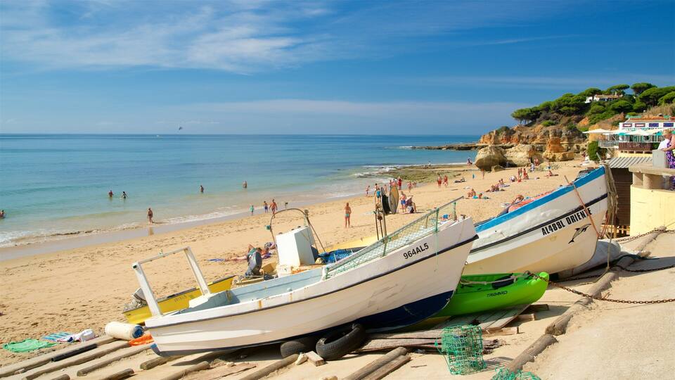 A beach with two boats, a sandy shore, and rocky cliffs in the background.