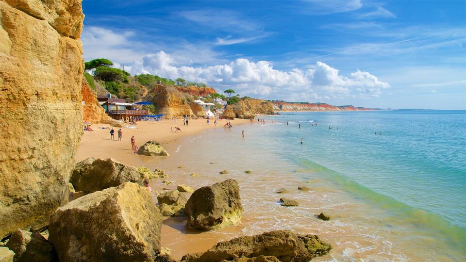 A beach with rocky shores, clear water, and a few people enjoying the sun.