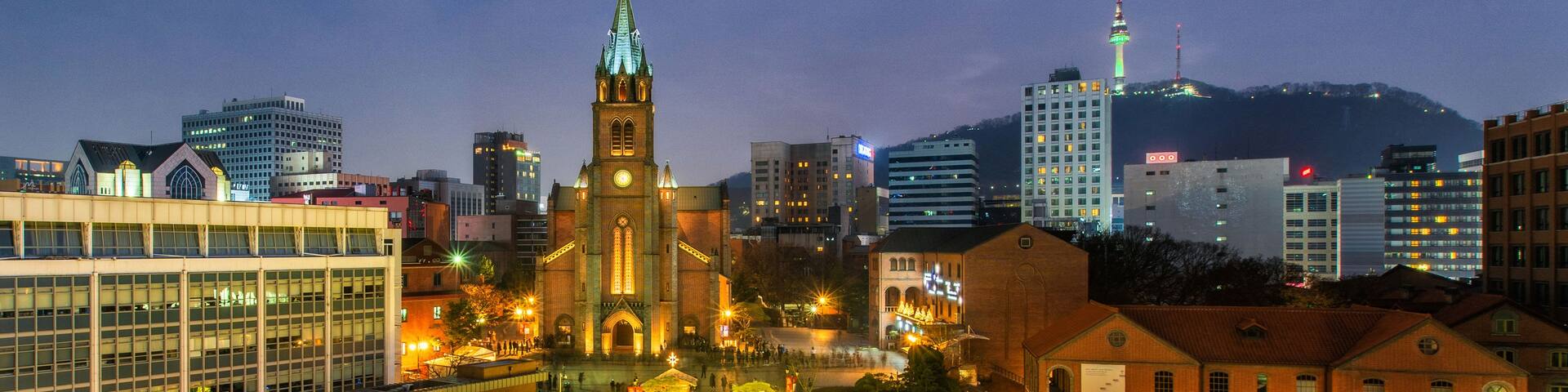 A cityscape at night with illuminated Christmas lights, a prominent church with a spire, and modern buildings.