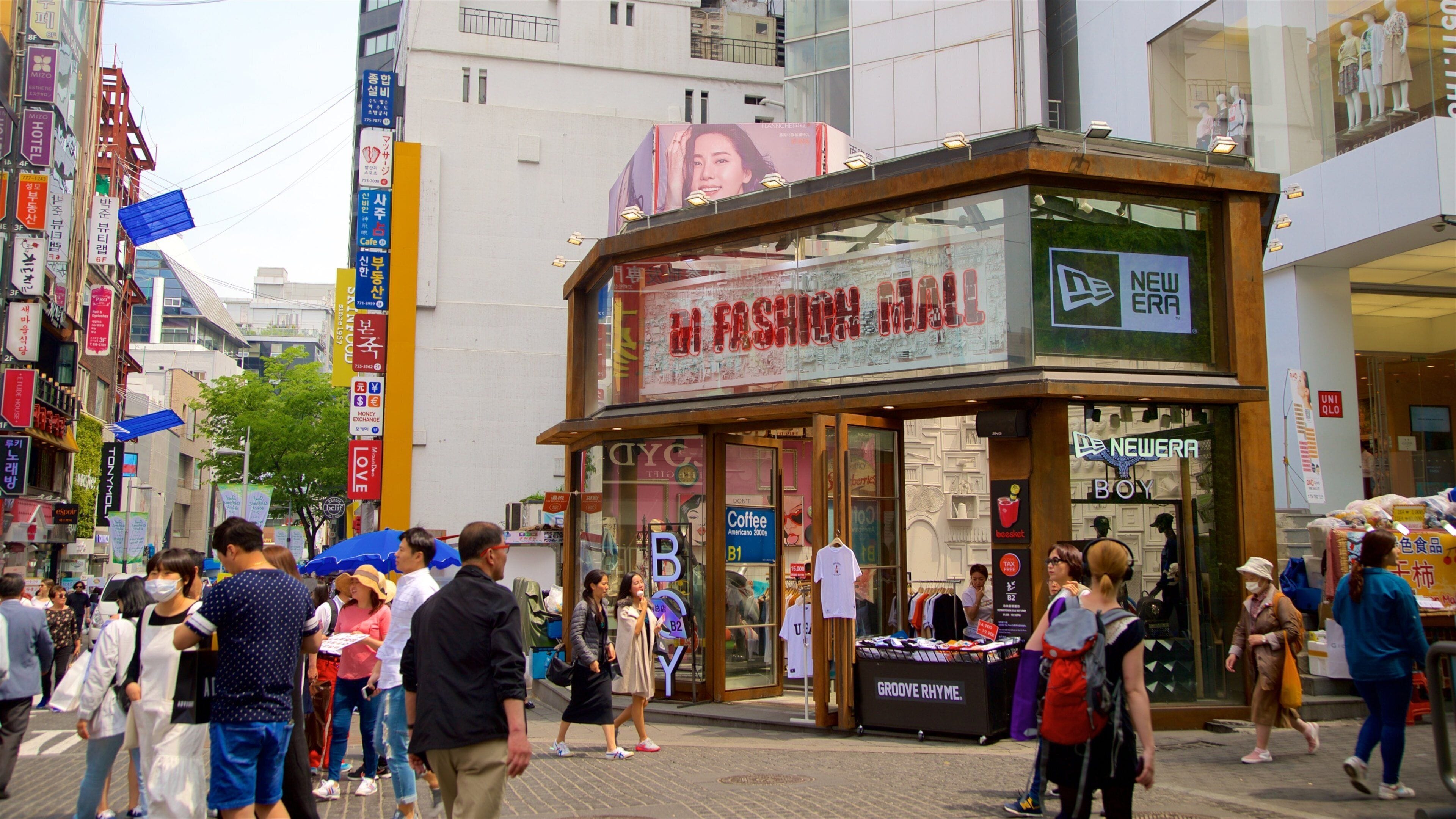 A busy street with a fashion store and various signs.