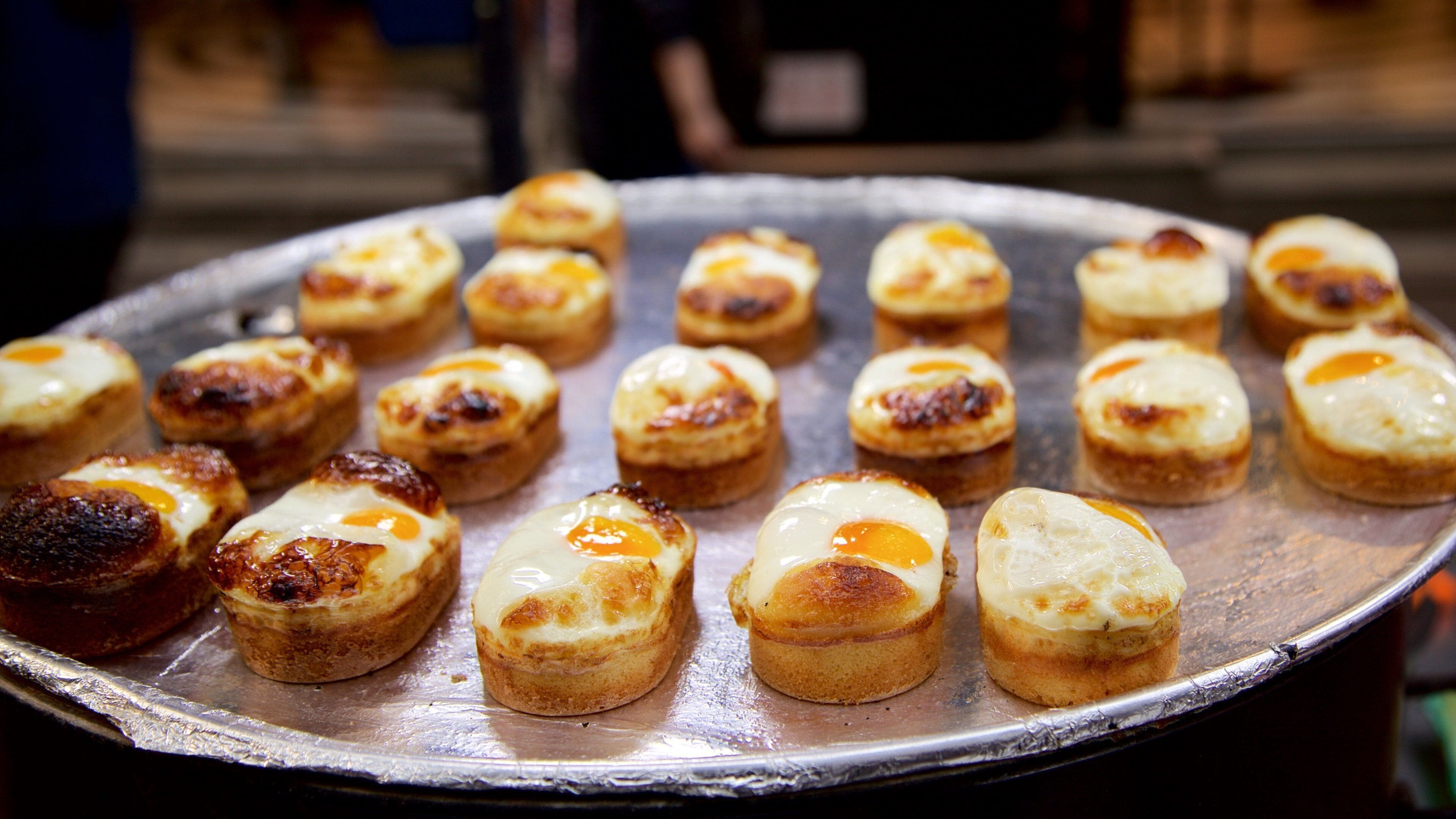 Un plateau de petites pâtisseries, chacune garnie d’un œuf.