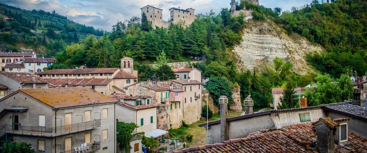 A historic castle on a hill overlooking a town with traditional buildings.