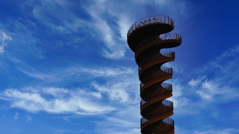 A spiral tower with a metal railing against a blue sky.