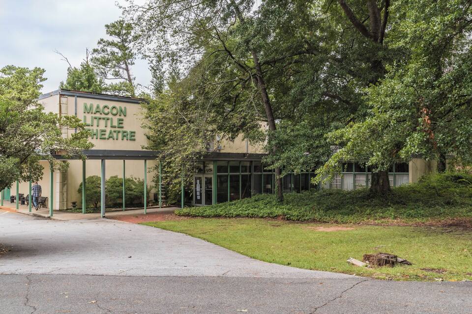 The exterior of the Macon Little Theatre with a covered entrance and surrounding greenery.