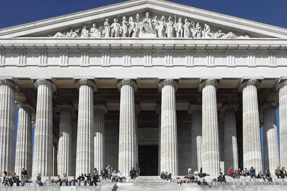 A neoclassical building with large columns and a detailed frieze of statues.