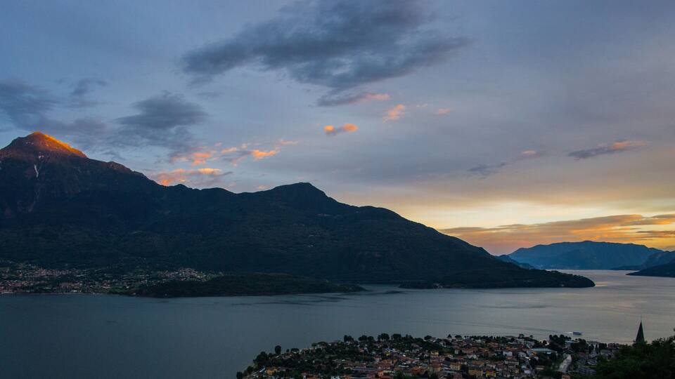 A mountainous landscape with a lake and a town at sunset.