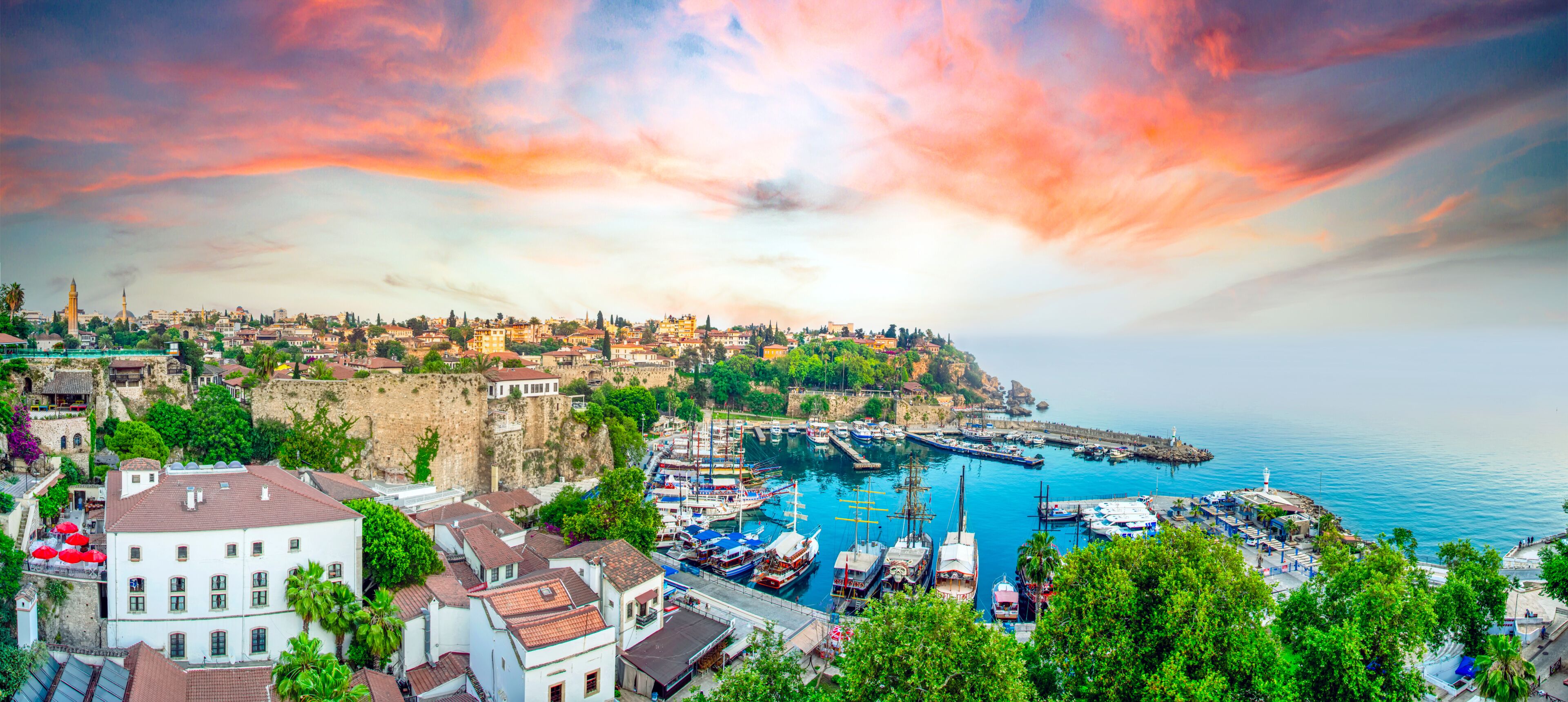 A coastal town with a harbor, historic buildings, and a sunset sky.