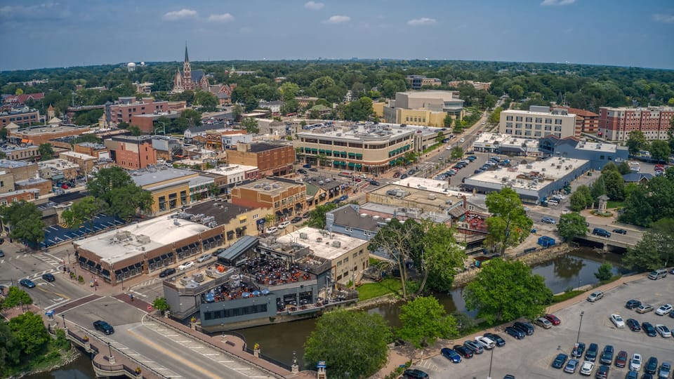 An aerial view of a city with a river, historic buildings, and a prominent church spire.