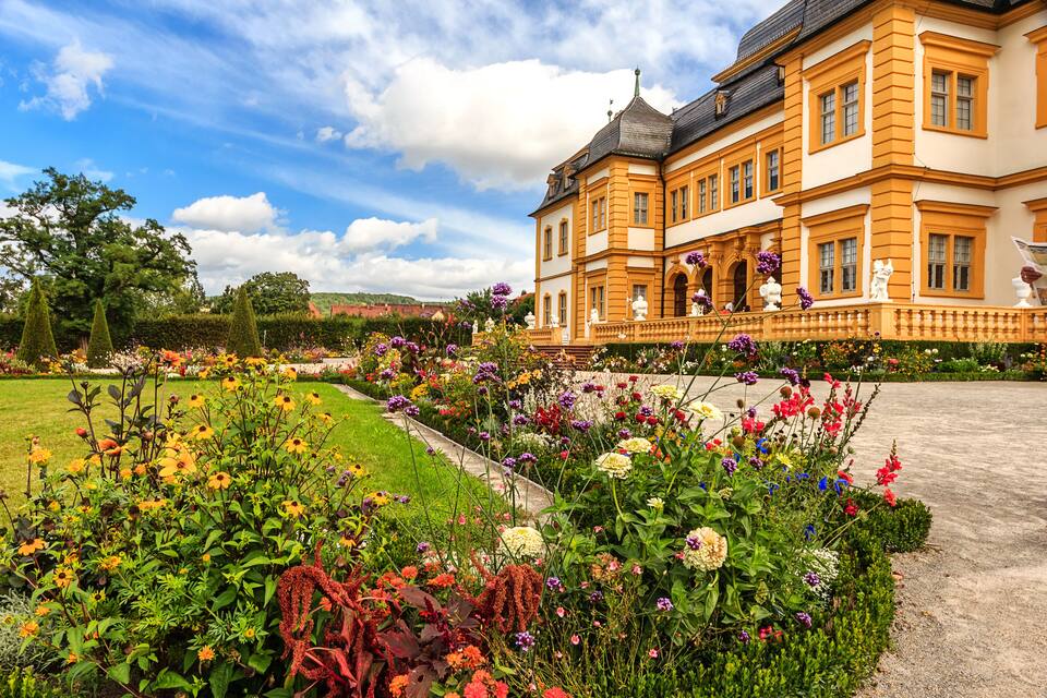 A large, ornate building with a manicured garden in front.