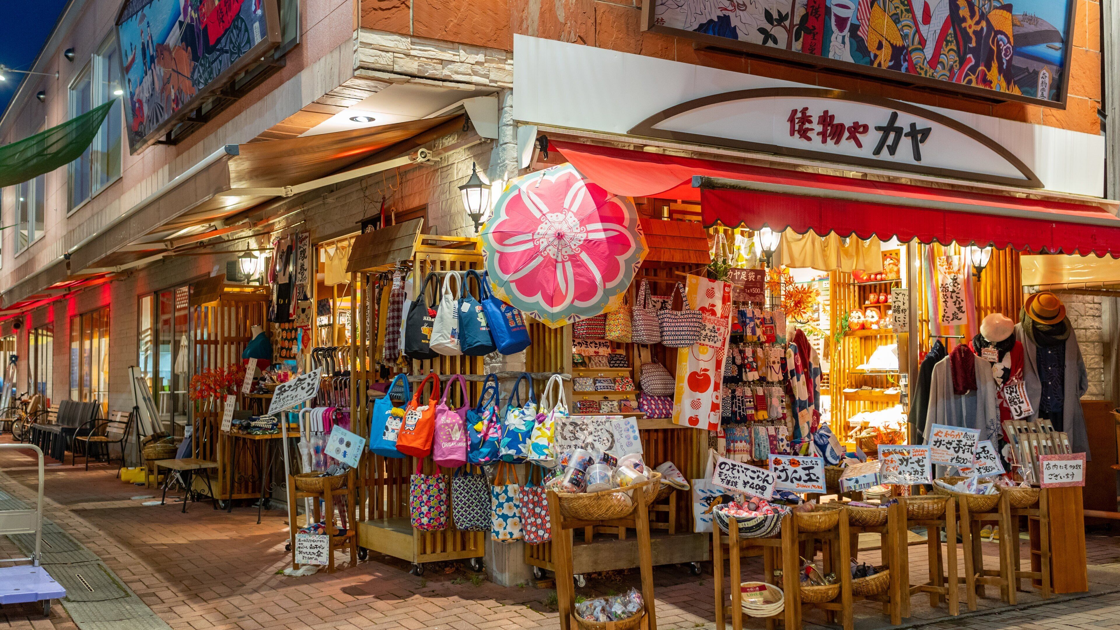 A street market with stalls selling bags and textiles.