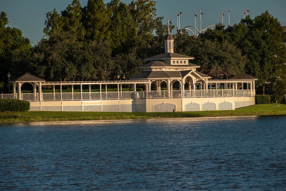 Un edificio junto al lago con un porche, rodeado de árboles y banderas.