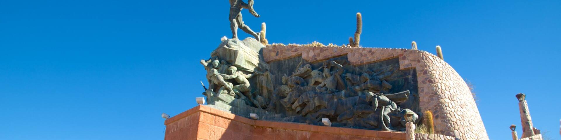 A historical monument with a statue of a man and a relief sculpture depicting a battle scene.