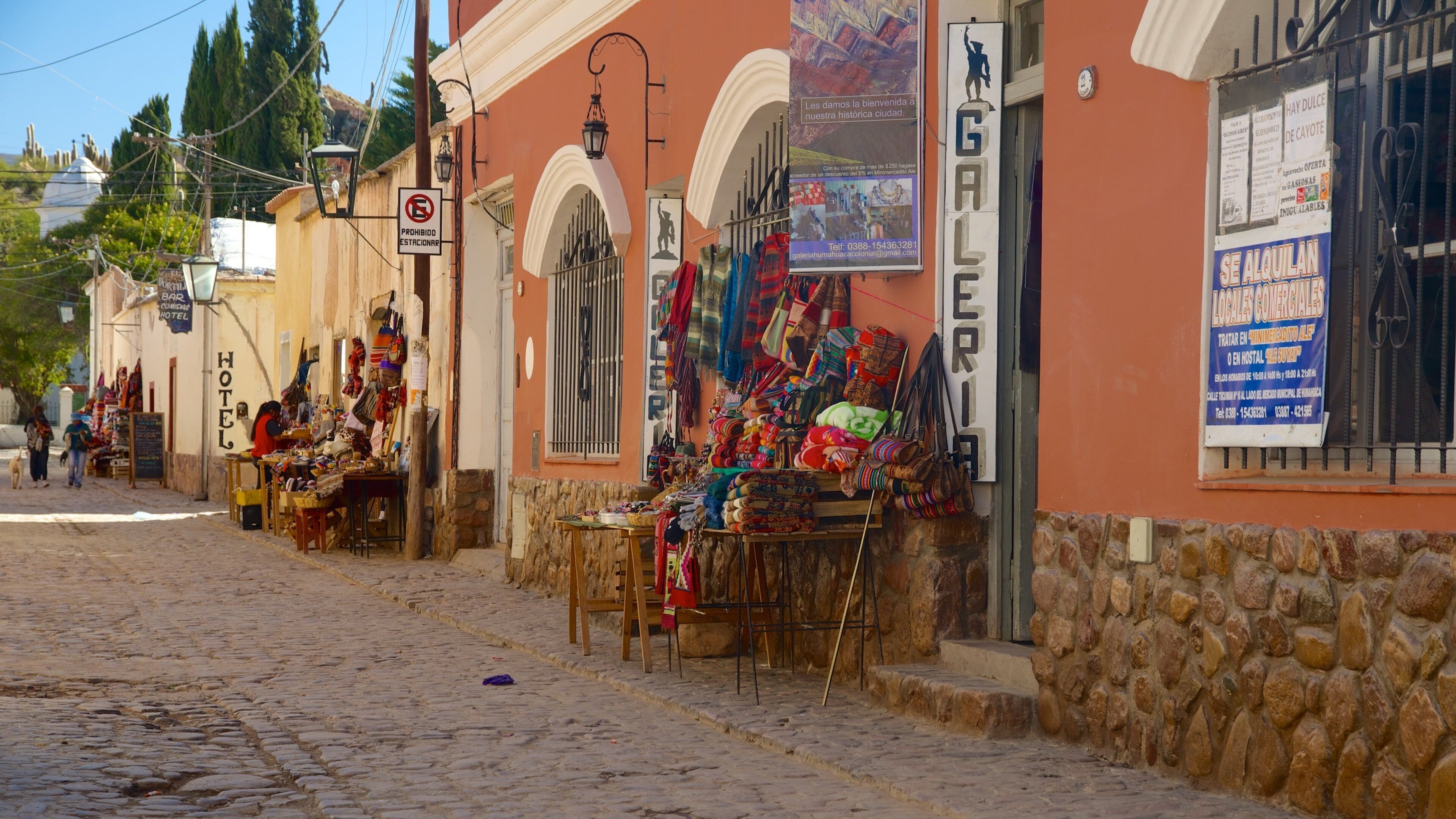 A cobblestone street with shops, a hotel, and a sign prohibiting parking.