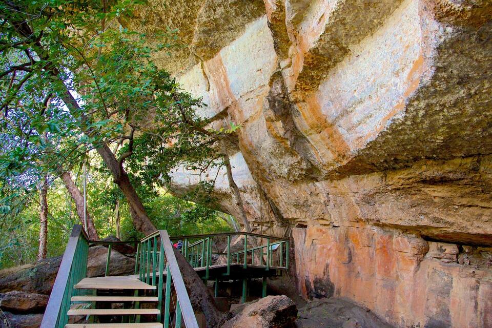 A rocky cliff with a wooden staircase leading up.