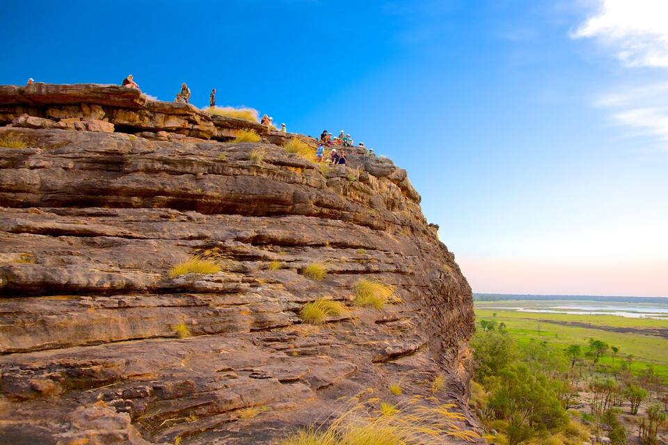 A rocky cliff with people standing on top.