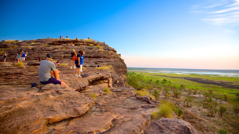A rocky cliff with people sitting and standing.