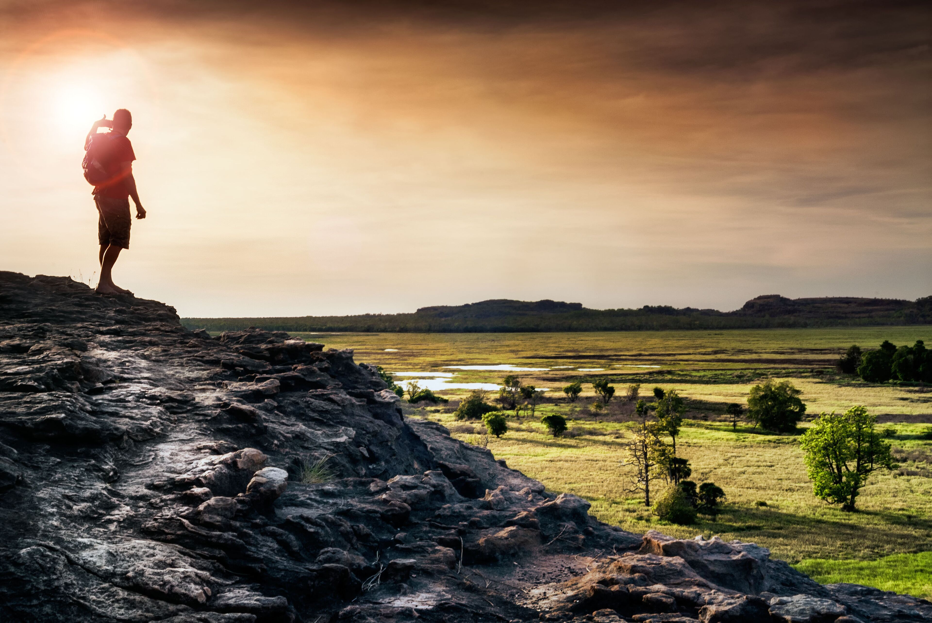 Lone figure watches the sunset from Ubirr rock looking down at the Nadab floodplains. Northern Territory, Australia; Shutterstock ID 616534646; Purchase Order: -
