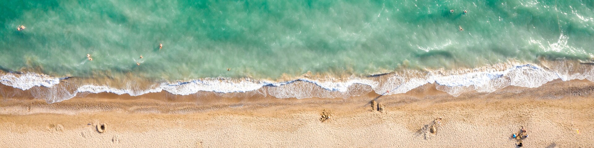 Una playa con sombrillas blancas y un mar turquesa transparente.