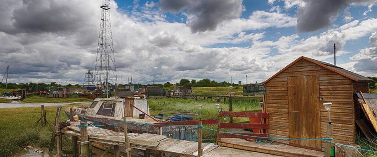 A rural landscape with a wooden structure, a metal tower, and a body of water.