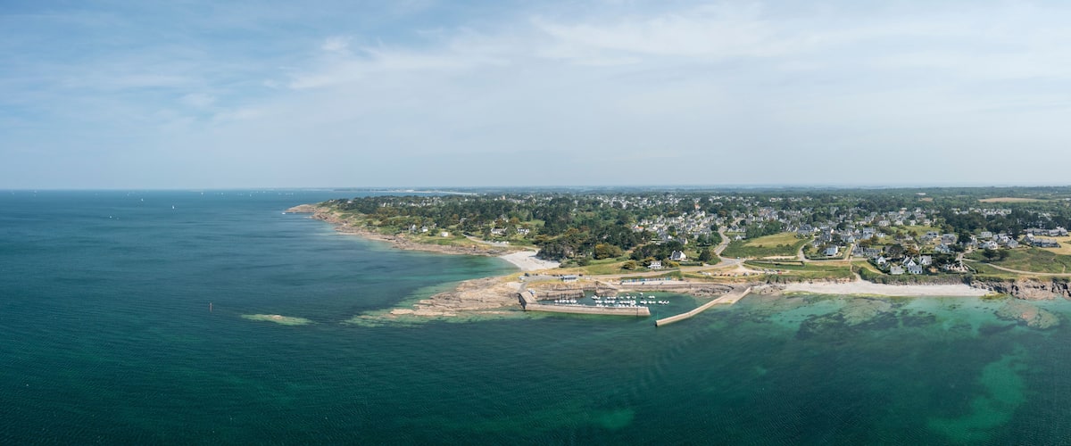 An aerial view of a coastal town with a marina, sandy beaches, and residential areas.