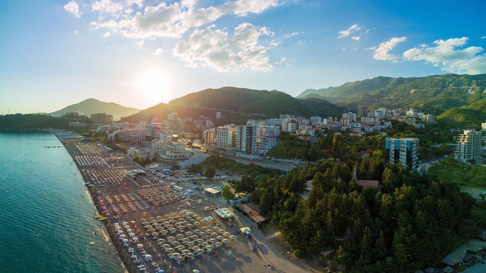 A coastal cityscape with a beach, parking lots, and residential buildings.