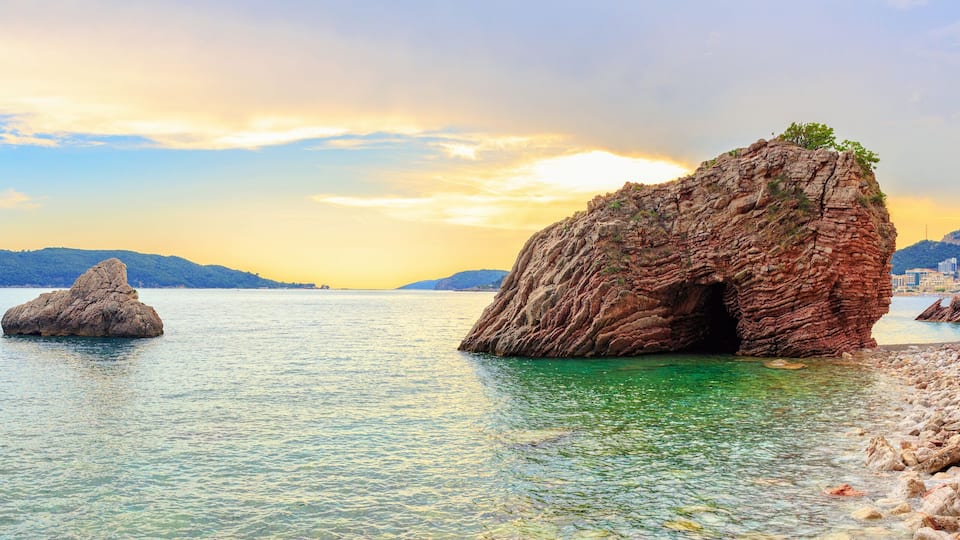 A coastal landscape with large rock formations and clear turquoise waters.