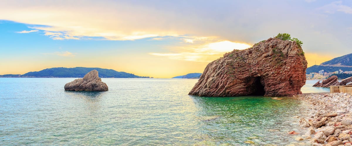 A coastal landscape with large rock formations and clear turquoise waters.