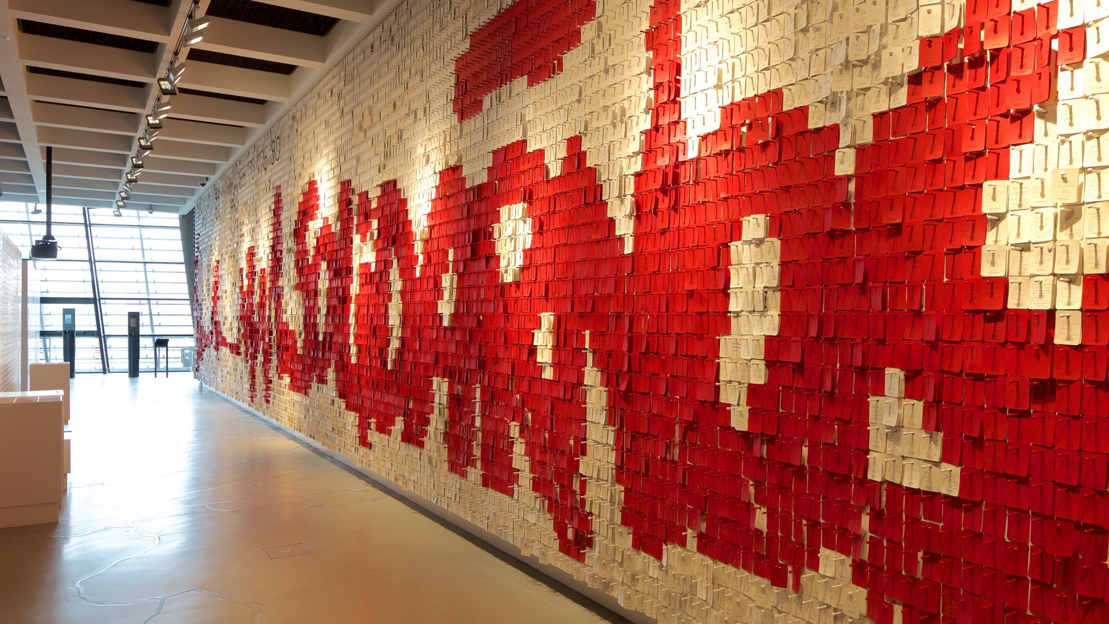A wall of red and white boxes with papers attached, in a modern interior space.