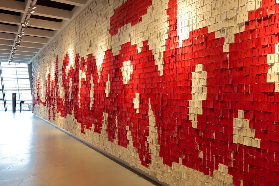 A wall of red and white boxes with papers attached, in a modern interior space.