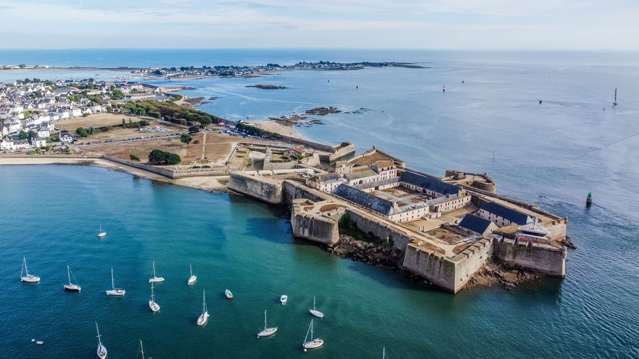 A coastal fortification with a harbor, surrounded by a town and the sea.
