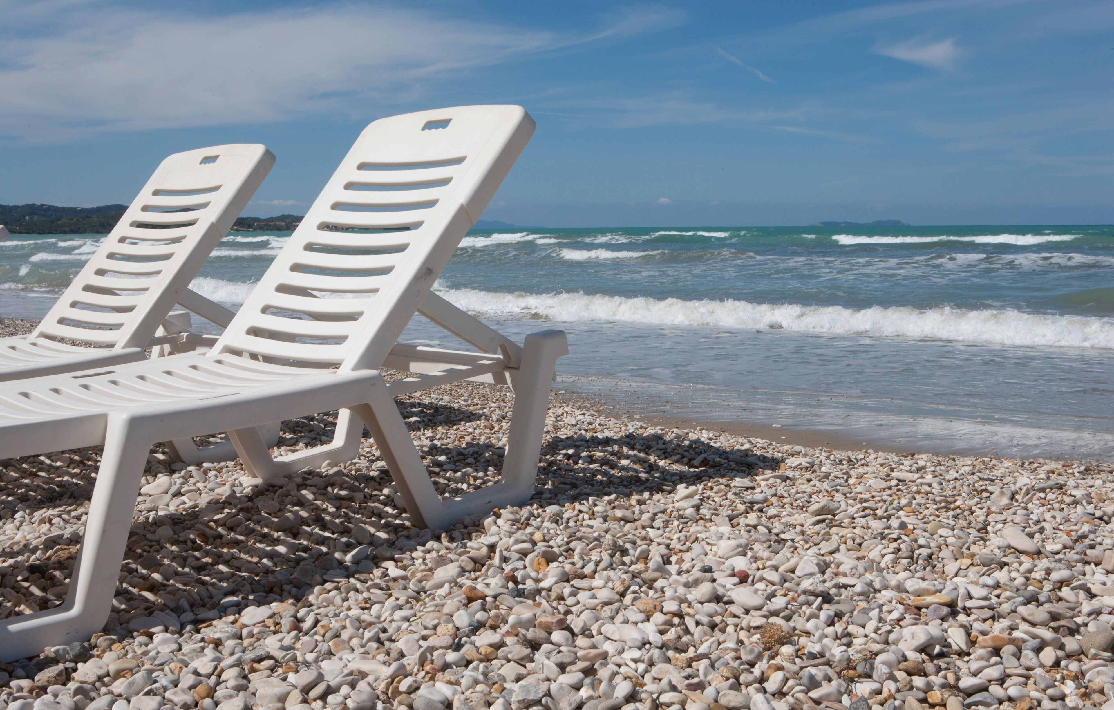 Deckchair at the beach of Acharavi Island of Corfu Greece. Waves at the coast. Mediterranean sea