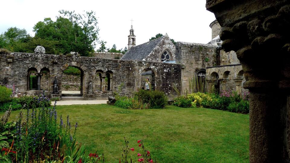 An ancient stone building with arched walkways and a tower.