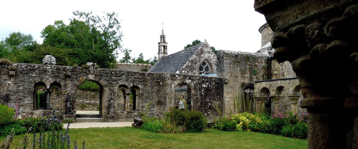 An ancient stone building with arched walkways and a tower.
