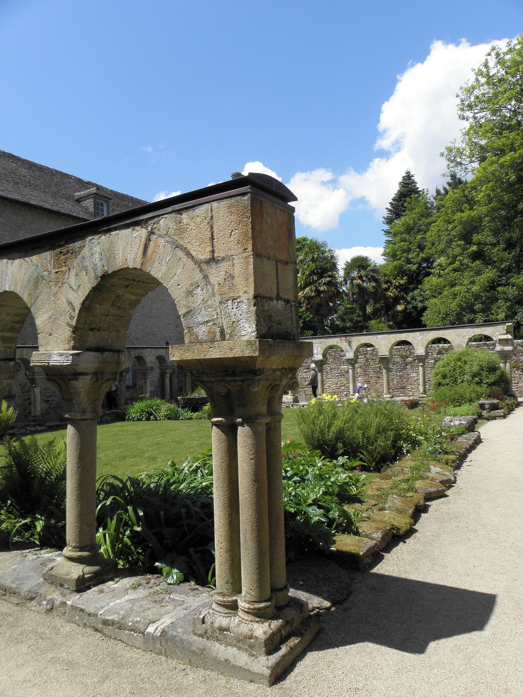 A stone structure with arches, a pathway, and lush greenery.