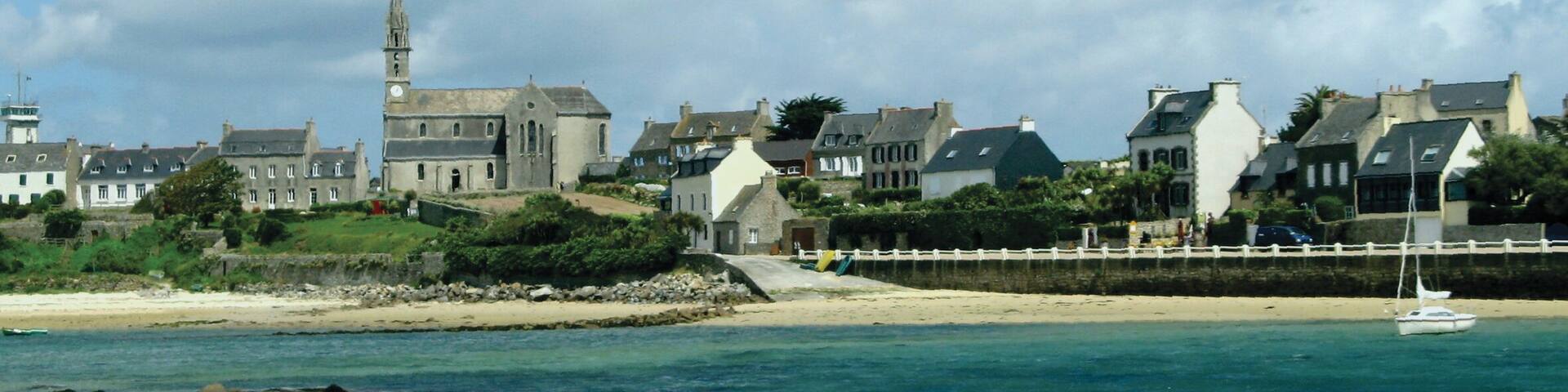 A coastal town with a prominent church and a sandy beach.