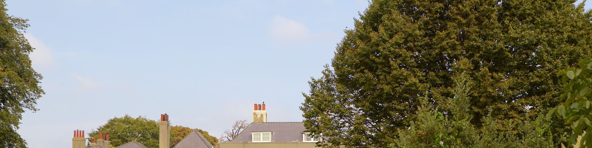 A large, multi-story house with green shutters and a well-maintained garden.
