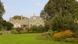 A large, multi-story house with green shutters and a well-maintained garden.