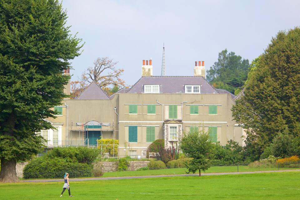 A large, historic building with green shutters and a tower.