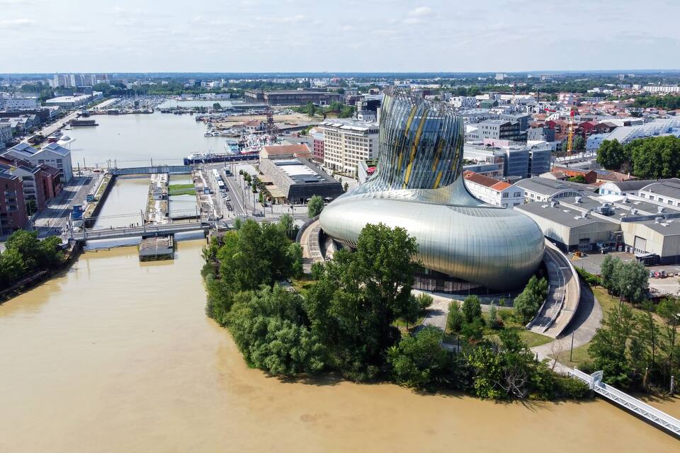 Un paysage urbain moderne avec un bâtiment au design original, caractérisé par ses lignes courbes, situé près d’une rivière.