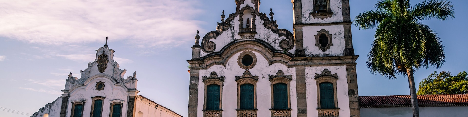 Una iglesia histórica con un campanario y una palmera al frente.