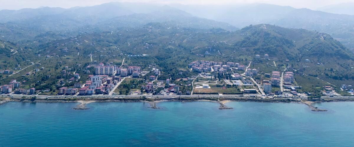 A coastal city with dense residential buildings, a marina, and surrounding mountains.