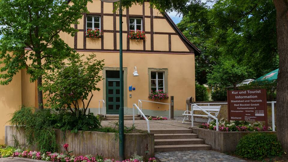 A traditional half-timbered building with flower boxes, a signboard, and a stone staircase leading to the entrance.