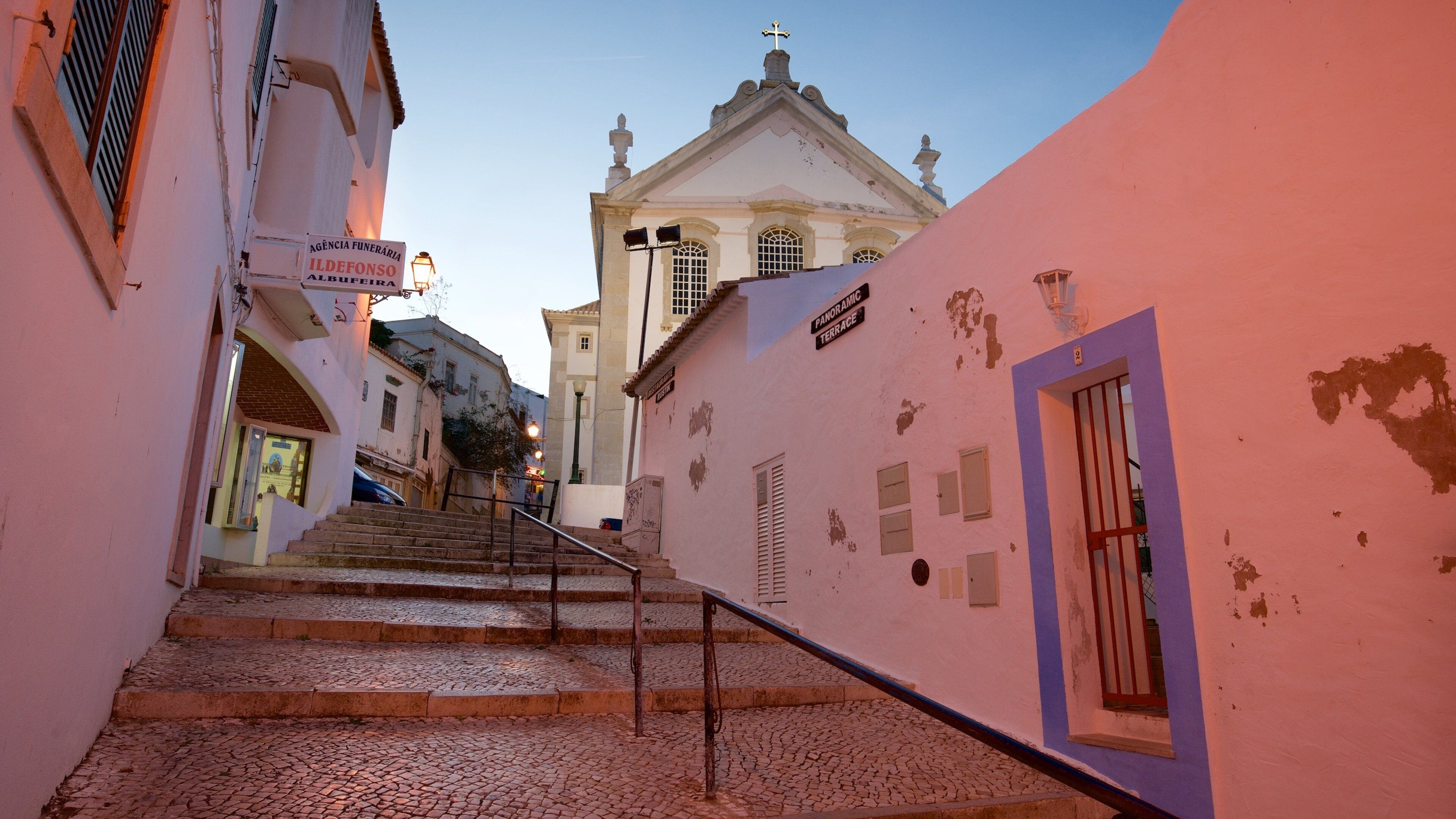 A cobblestone street leading to a church with a bell tower.