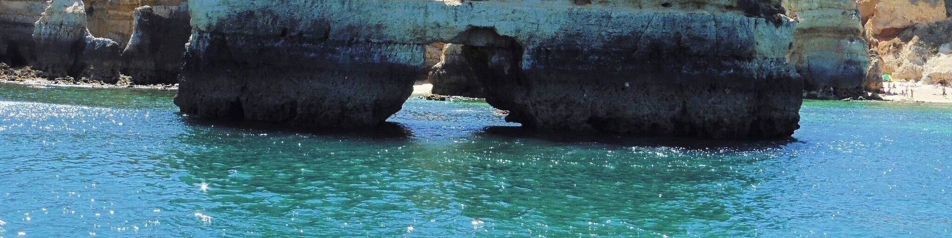 A coastal rock formation with a natural arch over turquoise waters.