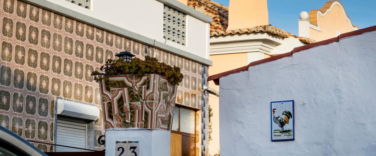 A building with a patterned facade, a number '23' sign, and a rooster mural.