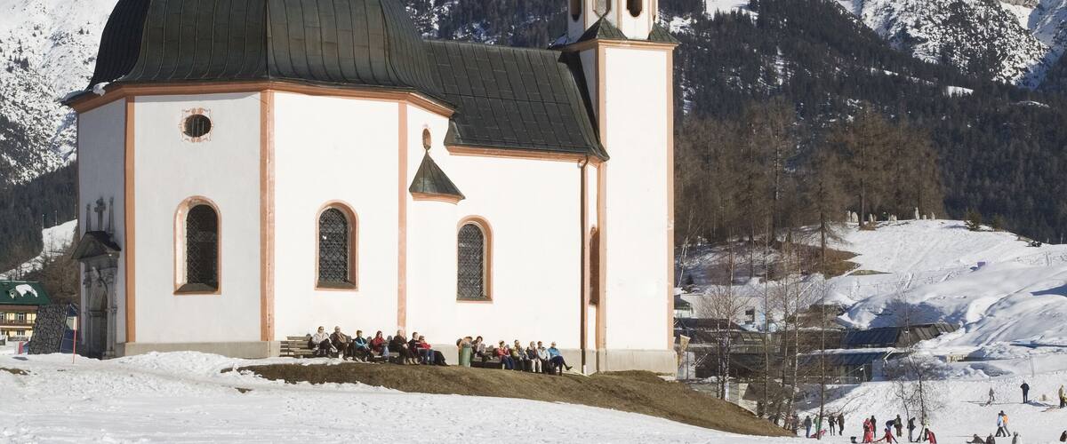 A snow-covered church with a dome and bell tower, surrounded by snow-covered mountains.